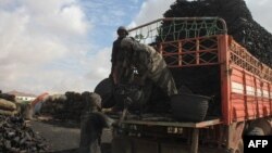 FILE - Laborers load a truck with charcoal in an open market in the Yakhshid district of Mogadishu on Oct. 26, 2014. 
