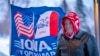 FILE - A man stands next to a flag that reading "Iowa for Trump" in Urbandale, Iowa, Jan. 11, 2024. Voters in the state are participating in caucuses on Jan. 15, 2024, that launch the Republican presidential nomination process.