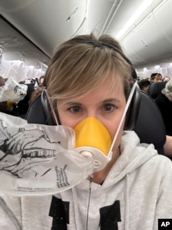 This image provided by Kelly Bartlett shows Bartlett wearing an oxygen mask on an Alaska Airlines Boeing 737 Max 9, Flight 1282 on Friday, Jan. 5, 2024. (Kelly Bartlett via AP)