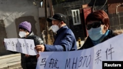 Anggota keluarga membawa spanduk saat berbicara kepada media setelah sidang pengadilan tentang kompensasi bagi mereka yang kehilangan orang yang mereka cintai dalam penerbangan Malaysia Airlines MH370 di Beijing, China, 27 November 2023. (REUTERS/Florence Lo)