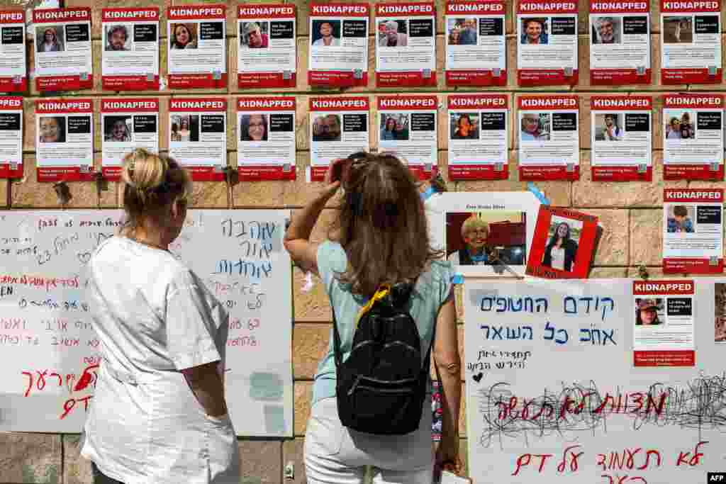 People look at posters showing the pictures of Israeli hostages held by Palestinian militants since the October 7 attack, near Azrieli Mall in Tel Aviv. (Photo by AHMAD GHARABLI / AFP)