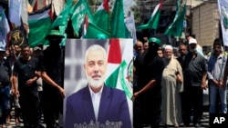 在黎巴嫩南部港口城市提尔的巴勒斯坦难民营，哈马斯成员举着哈马斯领导人伊斯梅尔·哈尼亚 (Ismail Haniyeh) 的画像抗议他被刺杀。(2024年7月31日)