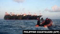 资料照：菲律宾海岸警卫队发布照片显示其巡逻艇驶过停泊在南中国海牛轭礁附近的多艘中国船只。（2021年4月14日）