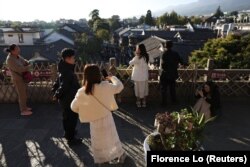 Visitors take pictures at a tower overlooking the old town of Dali, Yunnan province, China November 11, 2023. (REUTERS/Florence Lo)