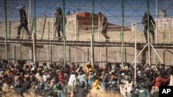 FILE - Polisi anti huru hara mengepung kawasan Melilla, Spanyol, setelah para migran tiba di daerah tersebut dan melintasi pagar yang memisahkan kantong Spanyol Melilla dari Maroko, 24 Juni 2022.