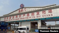 一警察面带口罩站在北京新发地农产品批发市场入口处。该市场因发现新形冠状病毒感染被关闭。