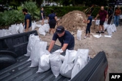 Seorang sukarelawan memuat karung pasir ke truk pick up untuk pelanggan menjelang kedatangan Badai Ian di Tampa, Florida pada 27 September 2022. (Ricardo ARDUENGO / AFP)