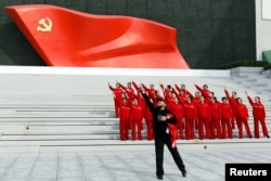 北京的中国共产党历史展览馆内参观者在中共党旗下摆姿势拍照。（2022年10月13日）