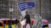 A protester adjusts an installation depicting Mark Zuckerberg surfing on a wave of cash constructed outside parliament in London, Oct. 25, 2021, where Facebook whistleblower Frances Haugen was due to testify.