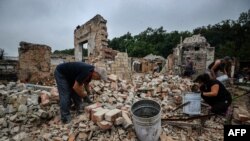 رضاکاران در حال پاکسازی آوار خانه‌ای استند که در اثر حملهٔ روسیه از بین رفته است