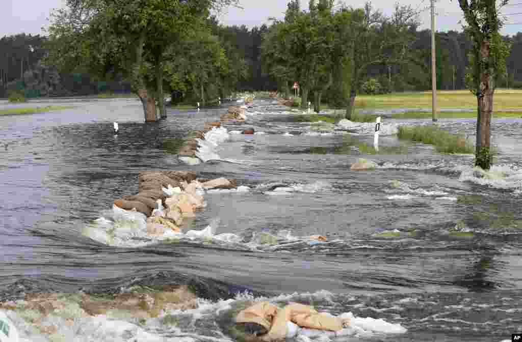 Karung-karung pasir yang digunakan untuk membendung air terhempas banjir di sebuah jalan antara Wulkau dan Kamern, Jerman. Air di Sungai Elbe, Sungai Danube, dan sungai lainnya meluap karena&nbsp; derasnya hujan, mengakibatkan kerusakan yang parah selama dua minggu ini di Jerman selatan dan timur laut.