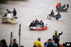 Orang-orang menggunakan perahu kecil untuk melewati jalanan yang terdampak banjir di Lismore, Australia, Senin, 28 Februari 2022. (Jason O'Brien/AAP via AP)