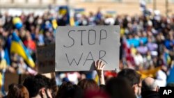 Një protestuese ngre një pankartë gjatë një mitingu kundër sulmit rus ndaj Ukrainës, në sheshin qendror Sintagma, në Athinë, të dielën, 27 shkurt 2022. (AP Photo/Yorgos Karahalis)