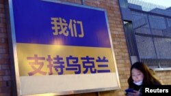 一名女子走过加拿大驻北京使馆外面挂出的支持乌克兰的标语牌（2022年3月2日）