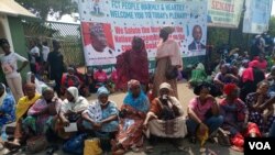 Protesters sit on the ground in front of the National Assembly gate after hours of demonstrations over gender bills by lawmakers in Abuja, Nigeria, March 2, 2022. (Timothy Obiezu/VOA) 