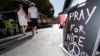 A couple walk through the empty flower market in the old city and near a sign which reads, "Pray for Nice" days after a truck attack on the Promenade des Anglais on Bastille Day killed scores and injured as many in Nice, France, July 17, 2016. 
