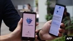 新加坡政府科技局工作人员展示新加坡为应对新冠病毒疫情新推出的接触者追踪智能手机APP（2020年3月20日），这款APP使用蓝牙技术。