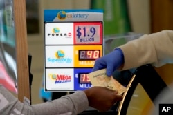 A customer is handed Powerball tickets purchased at Lichine's Liquor & Deli in Sacramento, Calif., Monday, Nov. 7, 2022. Monday night's drawing is estimated to be a record $1.9 billion. (AP Photo/Rich Pedroncelli)