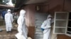 A burial team wearing protective clothing prepare to enter the home a person suspected of having died of the Ebola virus, in Freetown, September 28, 2014.