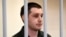 FILE - U.S. ex-marine Trevor Reed, charged with attacking police, stands inside a defendants' cage during a court hearing in Moscow, March 11, 2020. 