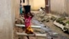 A girl carrying water on her head walks past sewage around houses in Abuja, Nigeria, Sept. 3, 2021. 