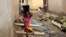 A girl carrying water on her head walks past sewage around houses in Abuja, Nigeria, Sept. 3, 2021. 