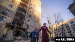 ស្ត្រី​ម្នាក់​នាំកូន​ជម្លៀស​ចេញ​ពី​អាគារ​លំនៅដ្ឋានដែល​រង​ការ​ខូចខាត​ដោយ​ការ​បាញ់​ផ្លោង ខណៈ​ការ​វាយ​ប្រហារ​របស់​រុស្ស៊ី​លើ​អ៊ុយក្រែន​នៅ​តែ​បន្ត​នៅ​ក្នុង​ទីក្រុងកៀវ ​ថ្ងៃ​ទី ១៦ ខែ​មីនា ឆ្នាំ ២០២២។