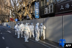身穿防护服的工作人员在上海一处因发现新冠疫情而被封闭的小区的屏障外。（2022年3月15日）