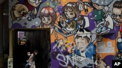 2022年3月22日，一名妇女和小孩戴着口罩走在香港的一条街道上。（美联社）