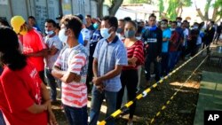 People line up to vote at a polling station during the election in Dili, East Timor, March 19, 2022.