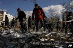 在基辅，当局说，一枚被乌克兰防空系统击落的俄罗斯导弹落在一处公寓楼群，人们在附近的医疗中西外清理破坏现场。(2022年3月17日)