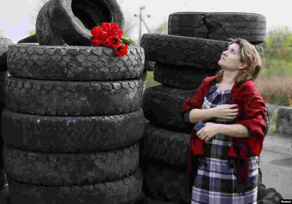 Warga di dekat pos pemeriksaan yang menjadi lokasi adu tembak dekat kota Slaviansk, Ukraina (20/4). (Reuters/Gleb Garanich)
