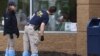 Members of the FBI look at bullet holes through the glass at the scene of a shooting at a Tops supermarket in Buffalo, New York, May 16, 2022.