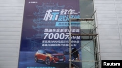 资料照：2020年8月9日，工人们在中国湖北省武汉市的一家经销店张贴了政府补贴东风标致汽车的巨幅海报。（路透社）