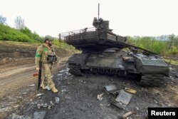 Український військовик поряд зі знищеним російським танком T-90M на Харківщині, 9 травня 2022. REUTERS/Vitalii Hnidyi