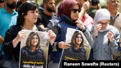 Des Palestiniens tiennent des photos de la journaliste d'Al Jazeera Shireen Abu Akleh, qui a été tuée par des tirs de l'armée israélienne lors d'un raid, à Naplouse, en Cisjordanie occupée par Israël, le 11 mai 2022. 