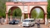 A man rides a motorbike taxi past police vehicles at the entrance of Shehu Shagari College of Education in Sokoto, Nigeria, May 13, 2022. 