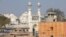 FILE -: A worker stands on a temple rooftop adjacent to the Gyanvapi Mosque in the northern city of Varanasi, India, December 12, 2021.