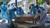 FILE - Health workers and relatives move a casket with the body of a COVID-19 victim for cremation, in Jammu, India, April 25, 2021.