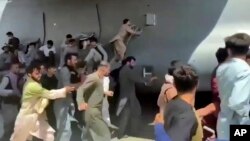 Desetine ljudi trče pored transportnog aviona C-17 američkog vazduhoplovstva dok letjelica rula pistom međunarodnog aerodroma, u Kabulu, Afganistan, 16. avgusta 2021.