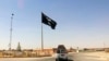 FILE - A motorist passes by a flag of the Islamic State group in central Rawah, 281 kilometers northwest of Baghdad, Iraq, July 22, 2014.
