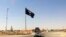 FILE - A motorist passes by a flag of the Islamic State group in central Rawah, 281 kilometers northwest of Baghdad, Iraq, July 22, 2014.