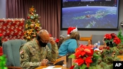 资料照：美国国防部发布的照片显示，在科罗拉多州彼得森空军基地的北美空防司令部里，基地官兵与志愿者在电话和电邮上回答来自世界各地儿童有关圣诞老人行踪的问询。（2021年12月24日）