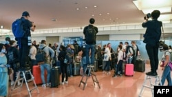 资料照：日本因新冠疫情边控外国游客来日本观光旅游两年半后，于2022年10月首次开放。新闻记者站在梯子上为抵达日本羽田国际机场的外国游客拍照。（2022年10月11日）