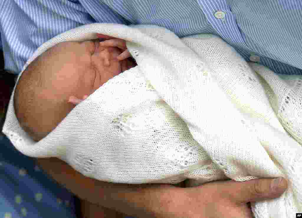 Britain's Prince William carries his new born son, the Prince of Cambridge, into public view for the first time, outside the Lindo Wing of St. Mary's Hospital, in London, July 23, 2013.