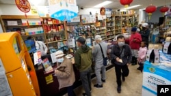 Madeline Copper, second from right, and her granddaughter, Lay-Lonnie, 5, stand in line to buy Powerball lottery tickets at the Wo Won Mini market in the Chinatown district of Los Angeles, Monday, Nov. 7, 2022. (AP Photo/Damian Dovarganes)
