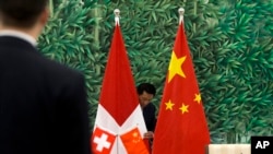 中国和瑞士官员会谈前，中国工作人员正在布置会场。桌上摆放的和背景是中国和瑞士两国国旗。