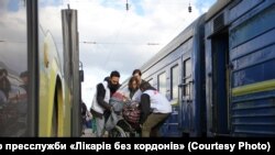 «Лікарі без кордонів» переносять людину в інвалідному візку з автобуса у потяг. Фото прес-служби "Лікарів без кордонів" через "Радіо Свобода"