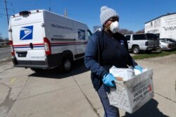 A United States postal worker outfitted with gloves and a mask makes a delivery in Warren, Michigan, April 2, 2020. The U.S. Postal Service has suspended mail to 22 countries due to the COVID-19 pandemic.