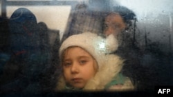 资料照：2022年3月2日，一名逃离乌克兰冲突的女孩在穿过帕兰卡附近的摩尔多瓦-乌克兰边境检查站后从一辆开往摩尔多瓦首都基希讷乌的巴士里朝外看。（法新社）